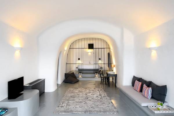 Innenraum des Ambassador Aegean Luxury Hotel & Suites mit weißem Interieur, Bett, Tisch, Stühlen und Fernseher.