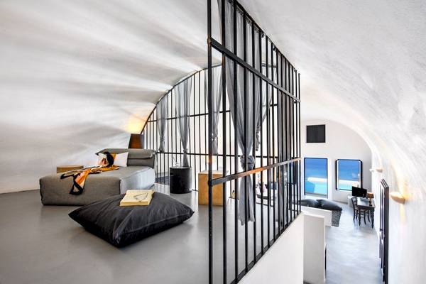Innenansicht eines modernen Zimmers im Ambassador Aegean Luxury Hotel & Suites mit einer Couch, Kissen und einer Aussicht auf das Meer.