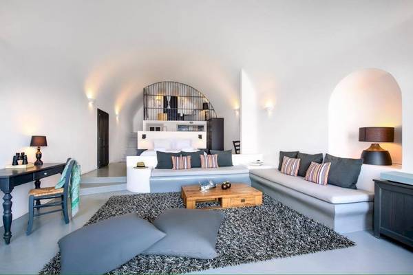 Innenbereich des Ambassador Aegean Luxury Hotel & Suites mit weißem Design, Bett, Sofa, Tisch, Lampen und Teppich.