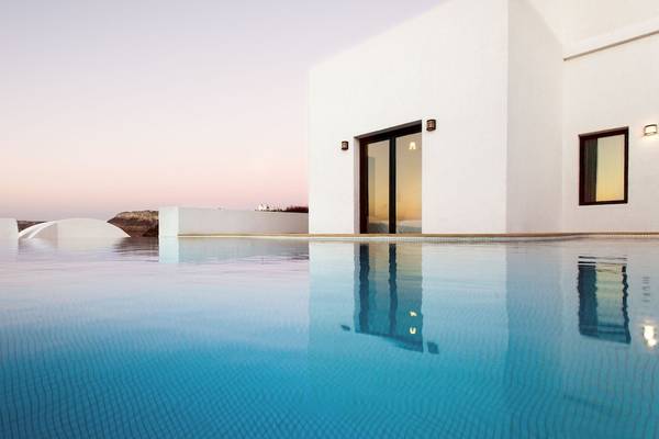 Pool vor einem weißen Hotel bei Sonnenuntergang