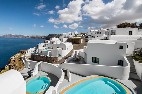 Luftaufnahme des Ambassador Aegean Luxury Hotel & Suites mit Blick auf das Meer und mehrere weiße Gebäude.