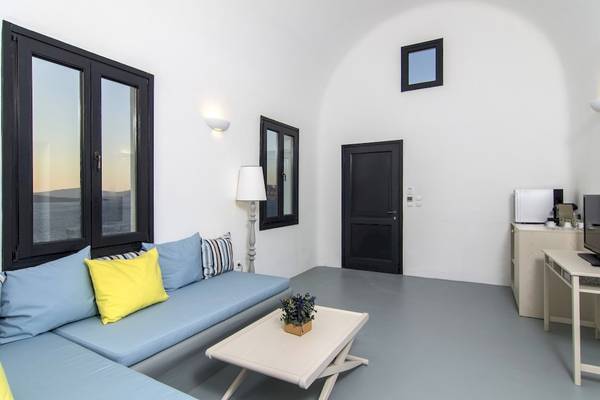 Wohnzimmer im Ambassador Aegean Luxury Hotel & Suites mit blauem Sofa, gelbem Kissen und weißem Tisch