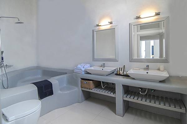 Badezimmer im Ambassador Aegean Luxury Hotel & Suites mit Badewanne, zwei Waschbecken und Toilette.