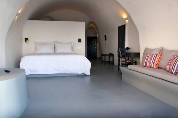 Luxuriöses Bettzimmer im Ambassador Aegean Luxury Hotel & Suites mit weißem Bett und Kissen, modernem Design und architektonischen Details.