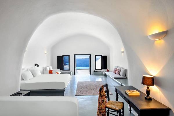 Innenansicht einer Suite im Ambassador Aegean Luxury Hotel mit weißen Wänden, Betten und Meerblick.