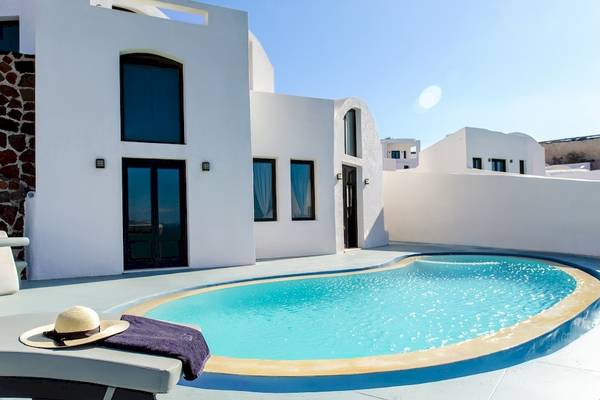 Eine weiße Villa mit einem Pool und einer Sonnenliege, auf der ein Hut liegt.