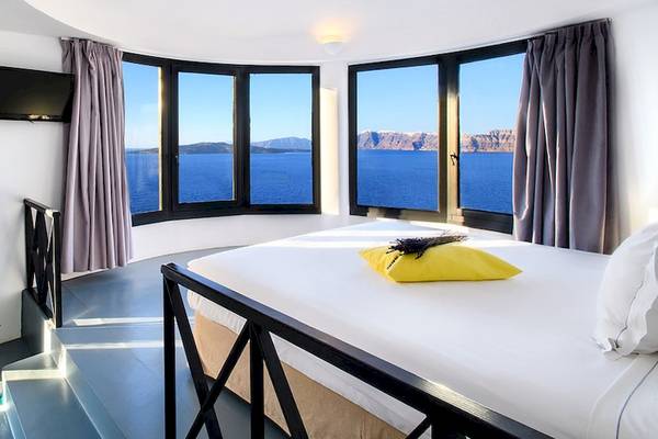 Zimmer im Ambassador Aegean Luxury Hotel mit Blick auf das Meer aus einem großen Rundbogenfenster.