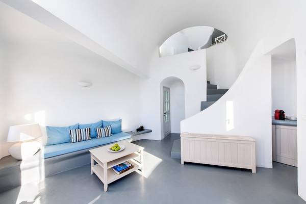 Innenbereich des Ambassador Aegean Luxury Hotel & Suites mit heller Einrichtung, blauem Sofa und weißem Tisch.
