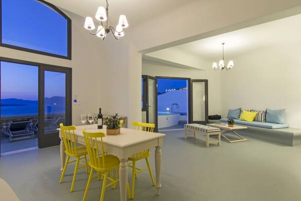 Innenraum des Ambassador Aegean Luxury Hotel & Suites mit Esstisch, gelben Stühlen und Aussicht auf das Meer.