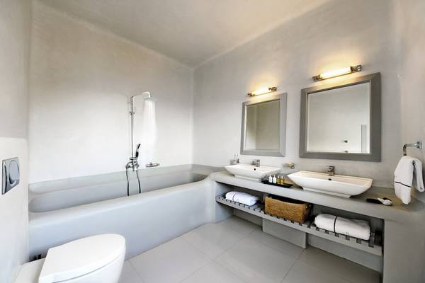Ein Badezimmer mit einer Badewanne, zwei Waschbecken und Spiegeln im Ambassador Aegean Luxury Hotel & Suites.