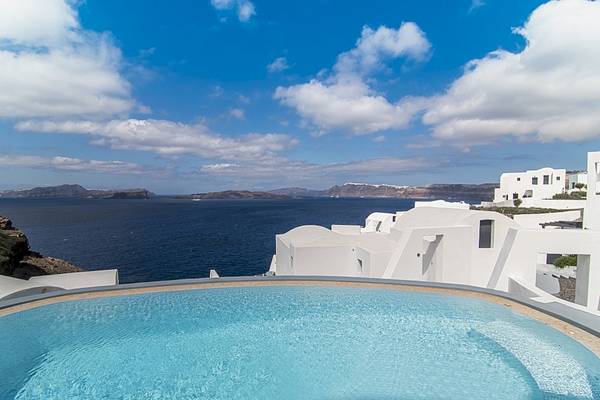 Aussicht auf das Meer von einer Hotelterrasse mit Pool und weißen Gebäuden.