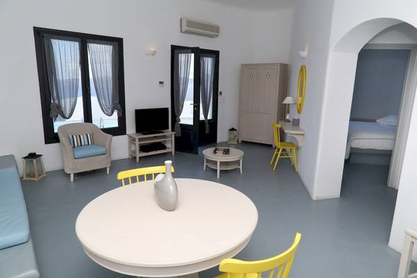 Innenraum des Ambassador Aegean Luxury Hotel & Suites mit Möbeln, Fernseher und einem Bett.