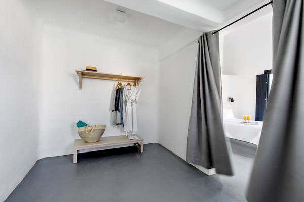 Ein schlichter Hotelbereich mit einem Kleiderschrank, einem Korb und einem Bett.