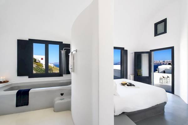 Modernes Schlafzimmer mit Meerblick im Ambassador Aegean Hotel & Suites mit einer Badewanne, Bett und offenem Fenster.