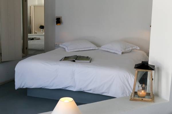 Bett im Ambassador Aegean Luxury Hotel & Suites mit weißen Laken und Kissen, einem offenen Buch und einer Laterne