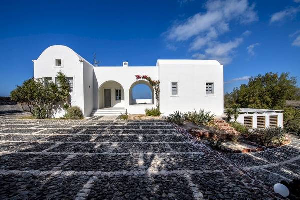 Außenansicht des Ambassador Aegean Luxury Hotel & Suites, ein weißes Gebäude mit einem gepflasterten Vorplatz und Pflanzen