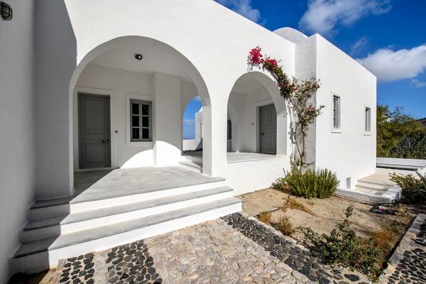 Das Ambassador Aegean Luxury Hotel & Suites, ein weißes Gebäude mit zwei Eingängen und roten Blumen.