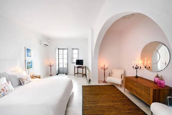 Innenansicht des Schlafzimmers im Ambassador Aegean Luxury Hotel & Suites mit weißem Bett, Dekor und Möbeln.
