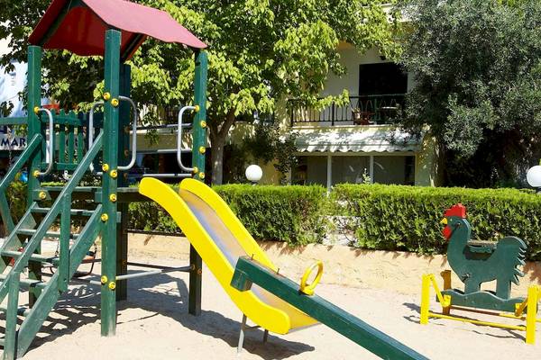 Spielplatz vor dem Hotel Acrotel Athena Pallas mit Rutsche und Hühnerfigur.
