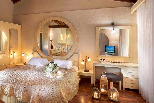 Schlafzimmer im Acrotel Athena Pallas Hotel mit großem Rundspiegel und Fernseher im Spiegel.