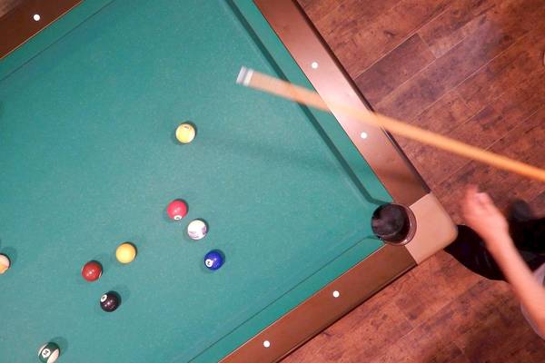 Ein Blick von oben auf einen Pooltisch mit bunten Kugeln und einem Stock.