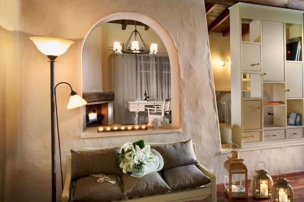 Innenansicht eines Zimmers im Acrotel Athena Pallas mit Couch, Kamin und Dekor.