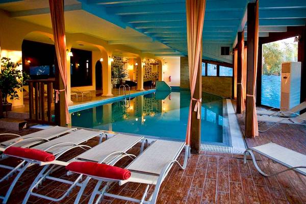 Pool-Loungebereich im Acrotel Athena Pallas Hotel mit weißen Sonnenliegen und blauem Wasser.