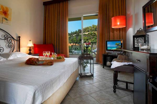 Ein elegantes Hotelzimmer im Acrotel Athena Pallas mit einem Bett, einem Balkon und einer Aussicht auf die Berge.