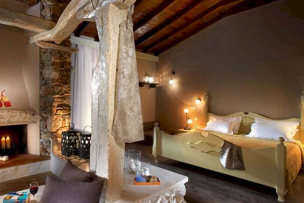 Schlafzimmer im Acrotel Athena Pallas mit Bett, Kamin, Kerzen und Leselampe.