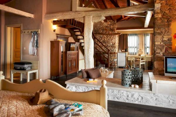 Innenansicht des Acrotel Athena Pallas Hotelzimmers mit Bett, Wohnzimmerbereich und Fernseher.