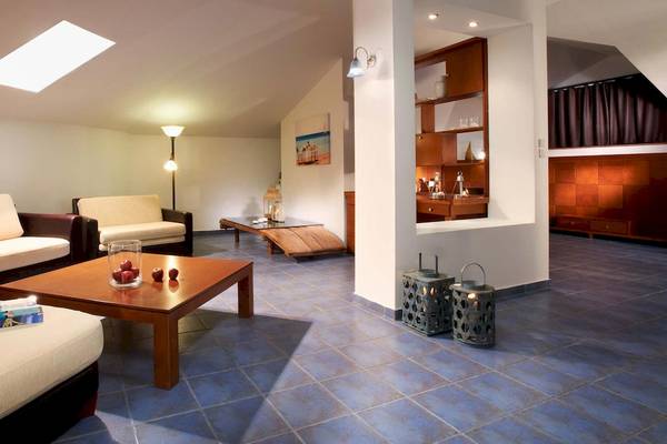 Innenansicht des Acrotel Athena Pallas Hotels mit Wohnzimmer, Couch, Tisch, Lampe und Dekoration.