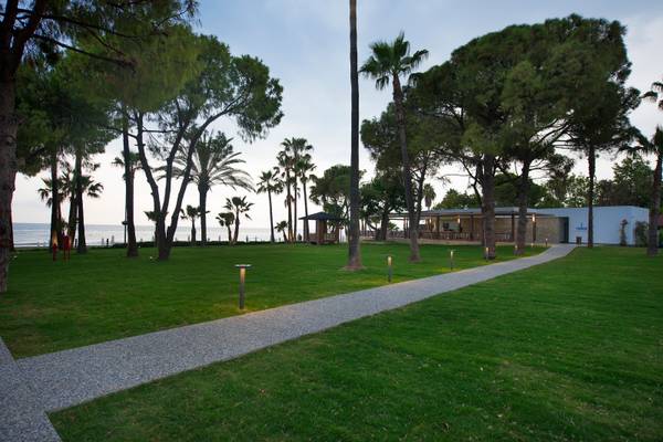 Ein gepflegter Garten mit verschiedenen Bäumen und einem Kiesweg zum Strand