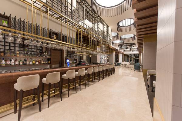 Bar im Acanthus Cennet Barut Collection Hotel mit hohen Stühlen und einer Theke voller Flaschen.