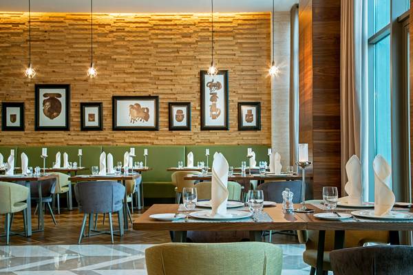 Innenansicht des Restaurants im Acanthus Cennet Barut Collection Hotel mit gedeckten Tischen und dekorierten Wänden.