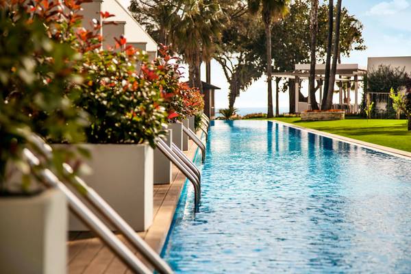 Außenpool des Acanthe Cennet Barut Collection Hotels mit blauem Wasser und grünem Rasen.