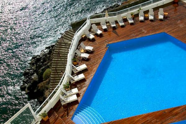 Aussicht auf den Swimmingpool des Vincci Tenerife Golf Hotels mit Lounge-Stühlen und Blick aufs Meer.