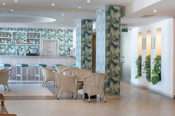 Innenansicht der Bar im Vincci Tenerife Golf Hotel mit blauen Stühlen und grünen Säulen.