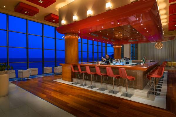 Innenansicht der Bar im Elysium Resort & Spa mit roten Stühlen und einer beeindruckenden Aussicht auf das Meer.