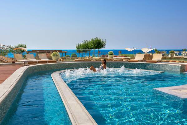 Eine Frau genießt den Blick auf das Meer im Swimmingpool des Elysium Resort & Spa.