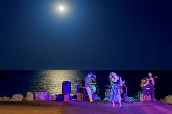Drei Musiker spielen bei Vollmond am Strand des Elysium Resort & Spa.