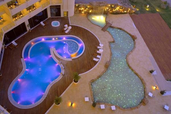 Elysium Resort & Spa Pool aus der Luft bei Nacht mit blauer und grüner Beleuchtung.