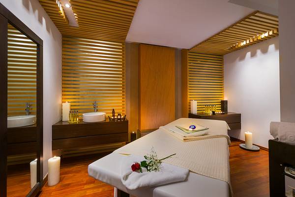 Massageraum im Elysium Resort & Spa mit weißem Bett, Kerzen und Rosen.