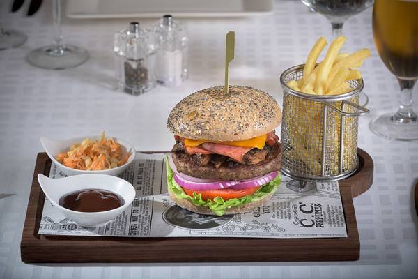 Ein Burger auf einem Holztablett mit Pommes und Getränken im Elysium Resort & Spa.
