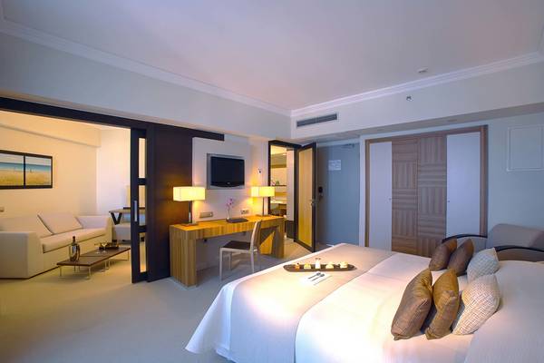 Innenansicht der Suite im Elysium Resort & Spa mit Schreibtisch, Bett und Wohnzimmerbereich.