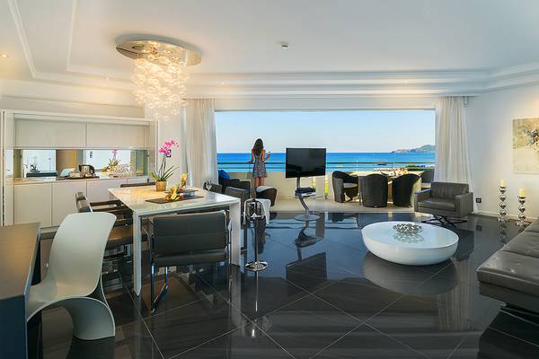 Wohnbereich des Elysium Resort & Spa mit Blick auf das Meer und eine Frau auf dem Balkon.
