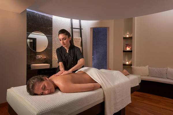 Massagebehandlung im Elysium Resort & Spa mit einer Therapeutin, die eine Frau massiert.