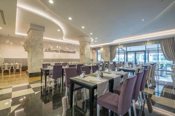 Innenansicht des Restaurants im Hotel Adalya Elite Lara mit gedeckten Tischen und Stühlen.