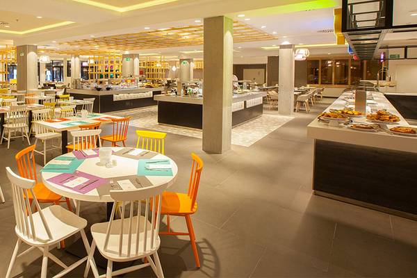 Innenansicht des Restaurants im Abora Continental by Lopesan Hotel mit bunten Stühlen und Tischen.