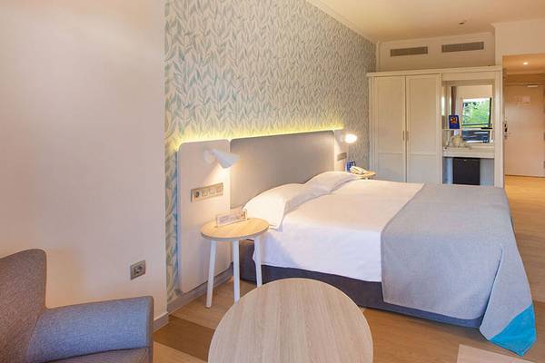 Innenansicht eines Hotelzimmers im Abora Continental by Lopesan mit einem Doppelbett, Nachttischen und Fernseher an der Wand.