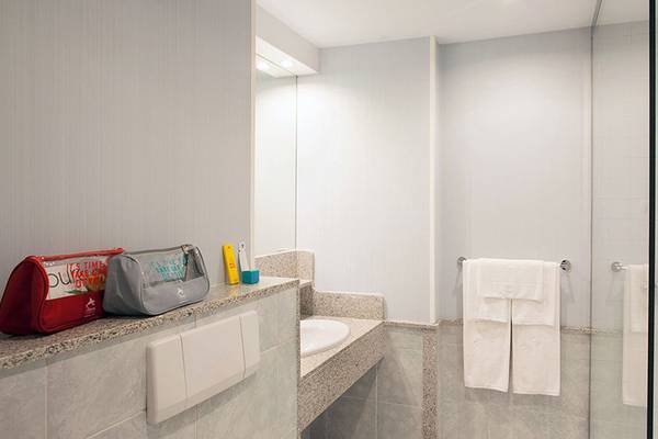 Badezimmer des Abora Continental by Lopesan Hotels mit Handtüchern, Shampoospender und Reisetasche.